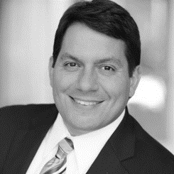 A man in suit and tie smiling for the camera.