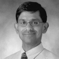 A man in glasses and a tie smiling for the camera.